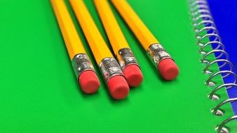 four school pencils on a green notebook