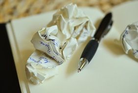 pen near a paper ball on a notebook