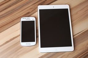 smartphone and tablet on wooden desk