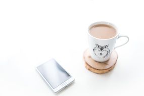 coffee mug with wolf and white smartphone