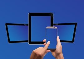 Mobile phone in hands on a background of tablets on a blue background