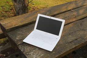 white laptop on a wooden table in nature