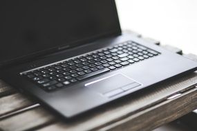 black laptop on a wooden table