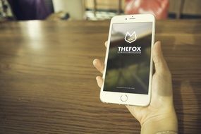 White mobile phone with the words "thefox" in the hands