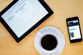 top view of a cup of coffee on the office desk on the background of the smartphone and tablet