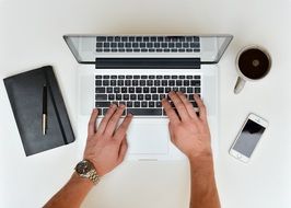 male hands on keyboard of laptop at desk