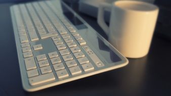 white keyboard and white cup on the table