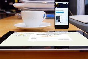 side view of a cup of coffee on the office desk on the background of the iphone and tablet