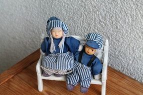 a pair of handmade dolls on a toy bench