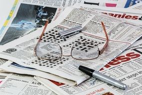 Glasses and a pen lie on the newspapers