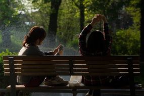 two girls on a park bench on a sunny day