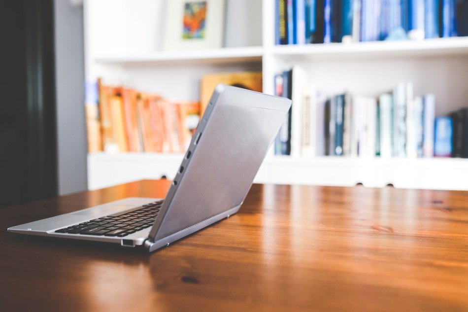laptop on the table against the background of the bookcase