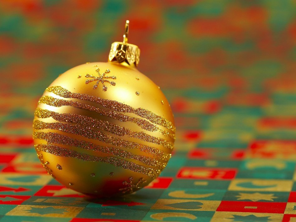 macro view of golden christmas ball on a multi-colored tablecloth