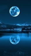 big full moon over a mountain lake