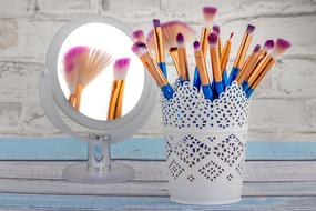 makeup brushes in a white decorative glass on the table