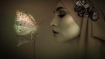 Profile portrait of the woman covered with cloth near the colorful butterfly