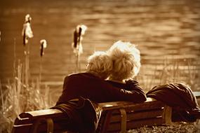 monochrome photo of an elderly couple on a bench by the lake