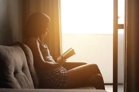 photo of a girl reading a book on the couch