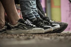 three pairs of sneakers on the feet of teens