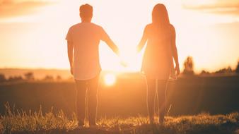 Photo of Man and Woman are Holding hands at the sunset