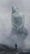 fantastic photo of a female sculpture in the fog in the mountains
