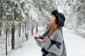 Girl is trying to catch the snow on the snowy landscape