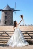 Bride with bouquet at wooden fence in countryside