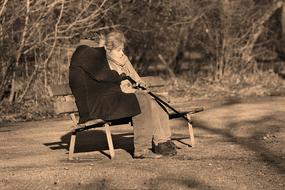 Retro photo of the elder man and woman, sitting on the bench in the park, near the plants