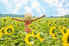 girl in a straw hat on a field of sunflowers under the summer sun