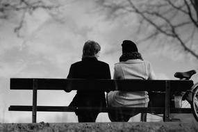 Man and Woman sit on bench in park