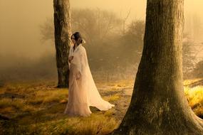 young girl in bridal gown walking through Mystical forest