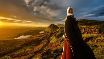 blonde girl looking at scenic Sunset in wilderness on landscape with the hills
