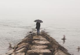 Girl stands under umbrella at stormy sea