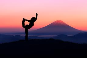 Silhouette of Woman doing Yoga excercise at purple landscape