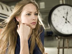 portrait of serious young girl beside of clock face