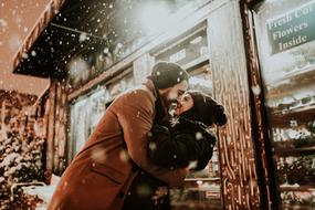 young couple kissing near shop display at winter