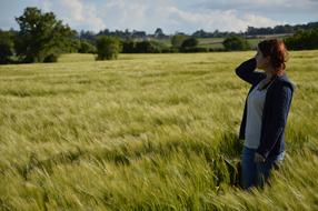 a girl standing on a field with wheat