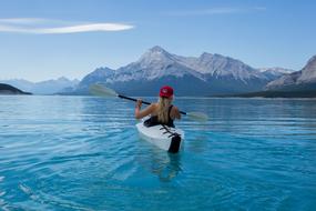 girl in a helmet on a canoe against the background of the Caucasus Mountains