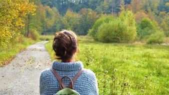 Woman with backpack walks Away at autumn forest