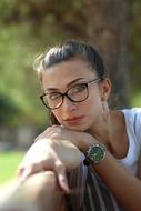 portrait of a girl with glasses on a bench in the park
