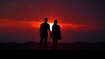 Silhouette of a couple, at beautiful, red sunset in the clouds