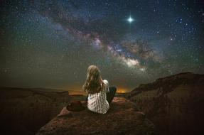 starry night sky above the girl in the mountains