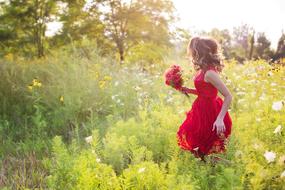 young woman in pretty red dress on the meadow