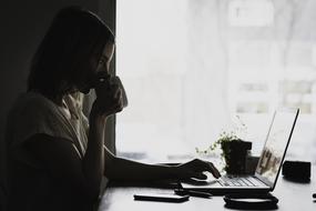 woman sitting with laptop and drinking coffee