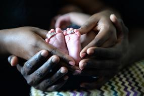 Babyâs feet with Wedding Rings on hands of young couple
