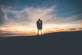 Silhouette of the kissing couple under the colorful sunshine