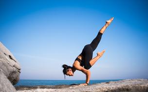 girl is doing yoga on a rolling pin on the shore of the ocean
