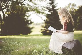blonde with a book in the garden in a blurred background