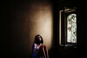 Teenager Girl sits on floor in dark room