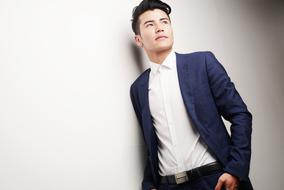 man in suit posing near the wall